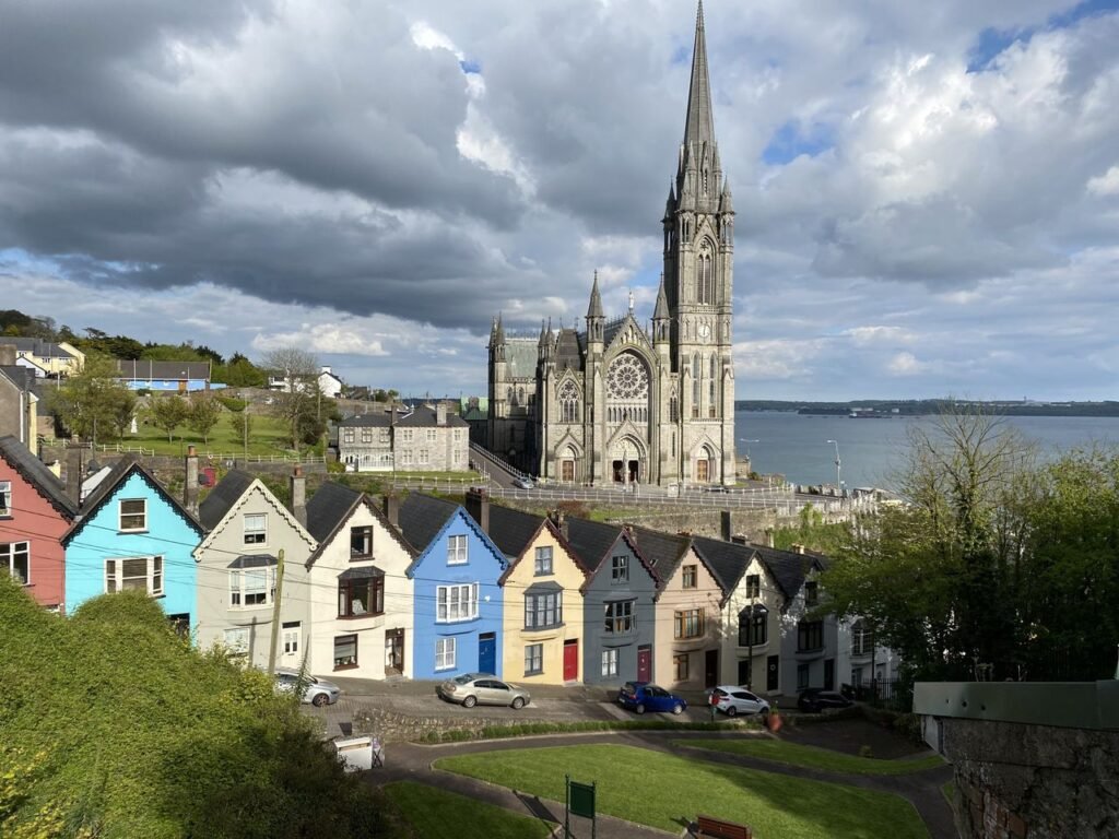 pexels-photo-10980287-10980287 Gothic architecture of St. Colman's Cathedral against a vibrant row of houses in Cobh, Ireland by the sea.