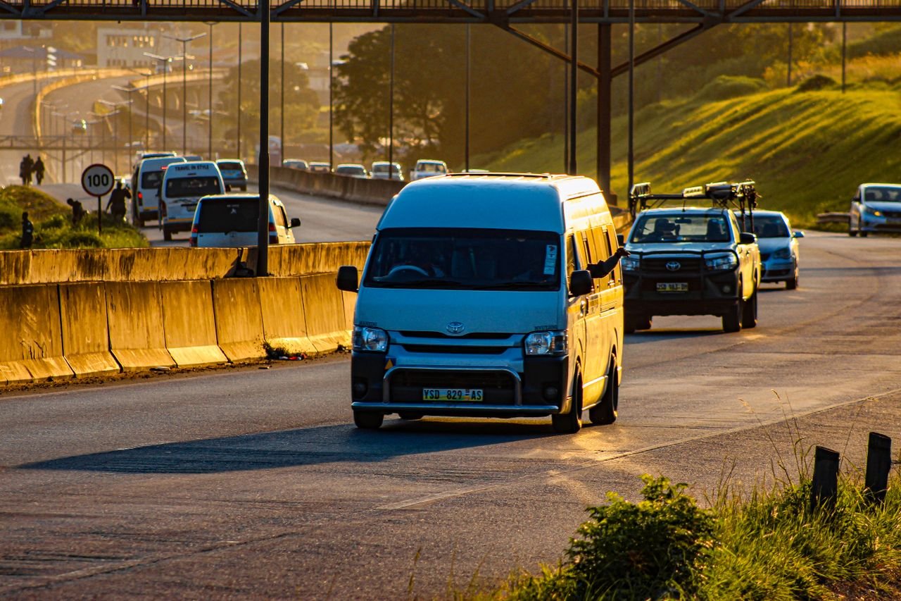 Minibuses and cars driving on a city road at sunset, capturing the vibrant golden hour light.