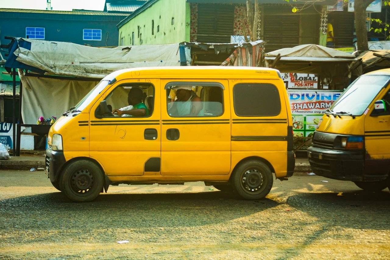 A yellow minibus taxi traverses a bustling street in Lagos, Nigeria, capturing daily urban life.
